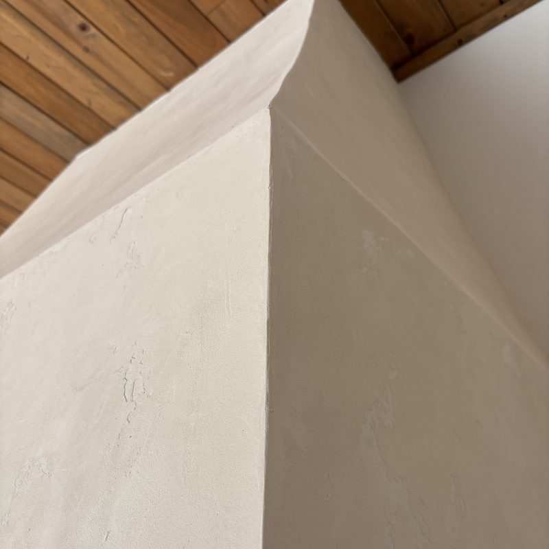 Close-up of a corner of the cream range hood showing its hand-textured surface