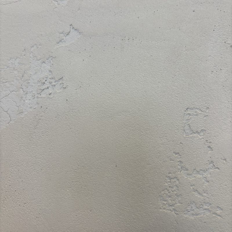 Extreme close-up of a cream plaster-look surface with textured patches, mid-process