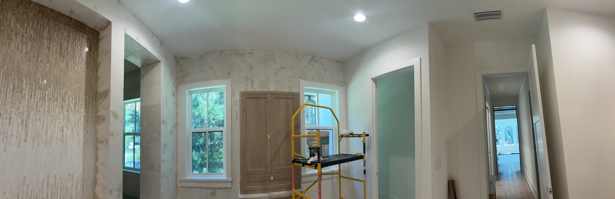 Panoramic view across the bathroom with the mosaic feature wall, a window, scaffolding, and a doorway to the hall